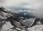 Hidden lake, 1200-ft below, appears as the initial clouds lift.  Mt. Torment and Forbidden Peak in the center, far distance.