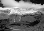 At Siyeh Pass proper (7750-ft) looking at the spindrifts ripping off Mt Siyeh. We&#39;re aided by a 40-mph tail wind. Frozen ground and grizzly tracks in the snow remnants...