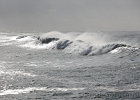 Waves roll past on their way to Agate Beach, reflecting the silvery sky and clouds.