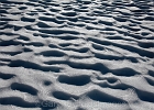 Snow scalloped by wind and rain and sun.